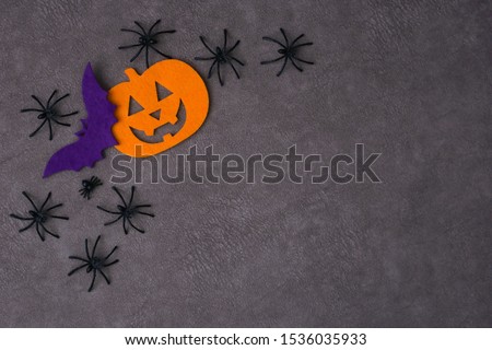 Top view Jack-o-Lantern, bat from felt next to spiders on brown background. Halloween concept. Place for text