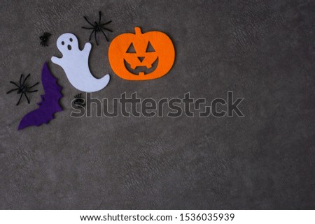 Top view Jack-o-Lantern, bat and ghost from felt next to spiders on brown background. Halloween concept. Place for text