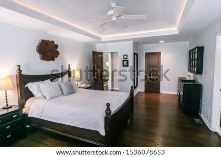 Master bedroom with king size bed and tray ceilings with uplighting and hradwood floors Royalty-Free Stock Photo #1536078653