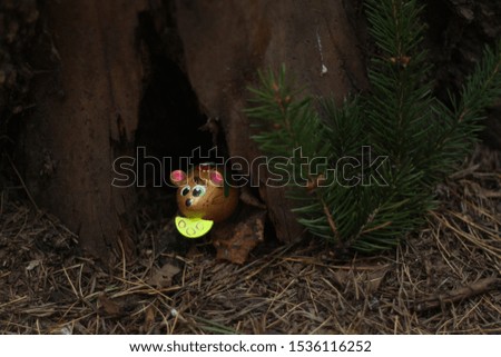 wooden mouse with cheese looks out of a forest hole