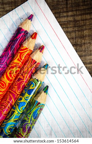 Colored wooden pencils on a sheet of white paper.
