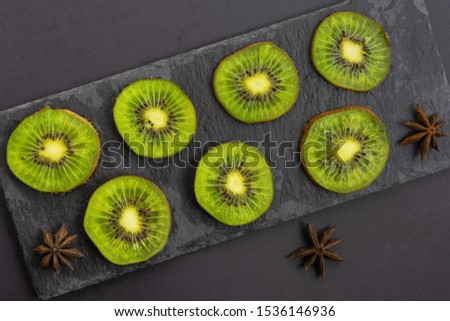 Freshly sliced kiwi fruit and orange for advertising and healthy eating, served on black shale dishes and decorated with star anise