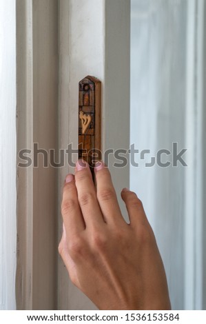 The girl touches the mezuzah with her finger. Translation of the letter Shin in Hebrew

