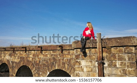 
The girl is sitting on an old, abandoned railway bridge.