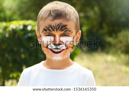 Cute little boy with face painting outdoors