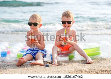 Happy kids sitting on an air mattress and drink juices. Summer vacation concept.
