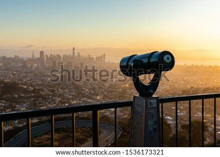 Monocular on popular view point on mountain of Twin Peaks called Christmas Tree point to see city and Bay Area of San Francisco at sunrise.