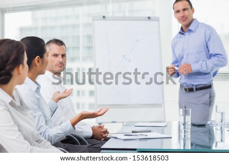 Businesswoman asking question during presentation in bright office