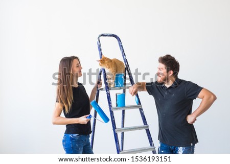 People, renovation, pet and repair concept - Portrait of funny man and woman with cat doing redecoration in apartment
