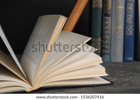 Open hardcover book on grey stone table, closeup