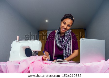 attractive woman seamstress next to the mannequin with sewing machine living room background in the studio copyspace