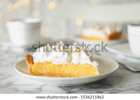 Plate with piece of delicious lemon meringue pie on white marble table