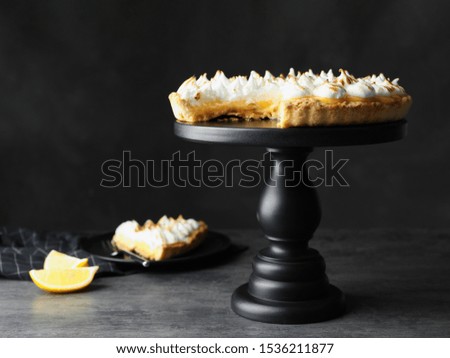 Stand with delicious lemon meringue pie on dark grey table, space for text