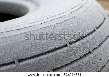 Car tire covered with frost blurred focus