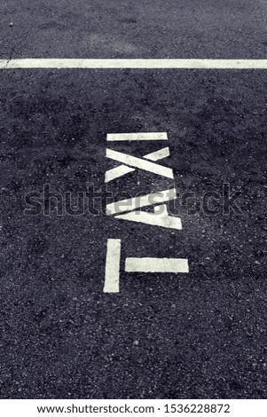 Taxi sign with white paint on asphalt