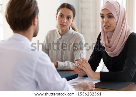 Asian muslim female hr manager interviewing job applicant consulting male client at diverse group meeting negotiations, ethnic businesswoman wear hijab speaking to partner, human resource concept Royalty-Free Stock Photo #1536232361