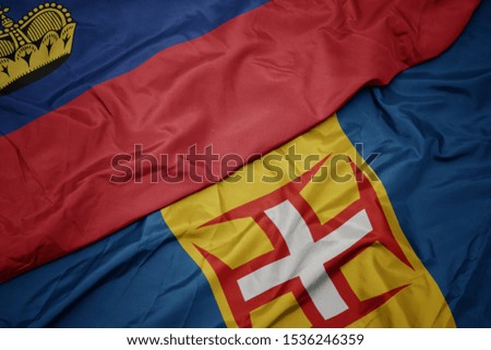 waving colorful flag of madeira and national flag of liechtenstein. macro