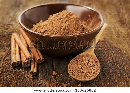 Cocoa powder and cinnamon sticks on wooden background