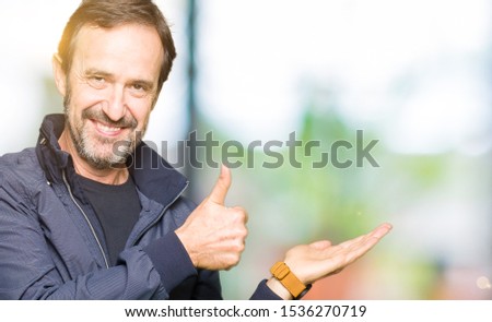 Middle age handsome man wearing a jacket Showing palm hand and doing ok gesture with thumbs up, smiling happy and cheerful