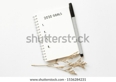 Text list 2020 goals on notepad with pen on white background,office desk.