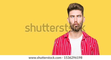 Young handsome man wearing red shirt making fish face with lips, crazy and comical gesture. Funny expression.