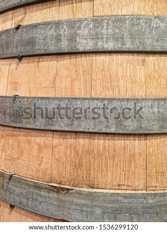 Close-up view of a wooden barrel with metal ring strips peeling off the paint.