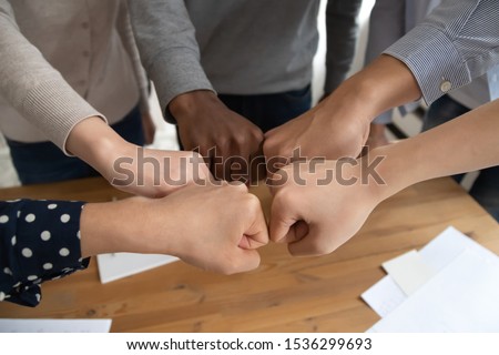Close up top view different ethnicity business people celebrating successful startup, diverse student touch fists hold together make circle as symbol of responsibility and equal opportunities concept Royalty-Free Stock Photo #1536299693