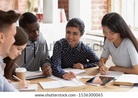 Focused multi national students studying together, team of girls and guys led by indian leader help with home work understanding, share ideas, offers creative approach to solve math challenge concept Royalty-Free Stock Photo #1536300065