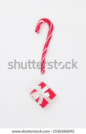 Question mark from Christmas present with candy cane on white background. Gift choice concept. Top view, flat lay, copy space, vertical format