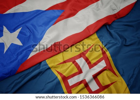 waving colorful flag of madeira and national flag of puerto rico. macro