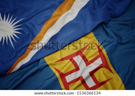 waving colorful flag of madeira and national flag of Marshall Islands . macro