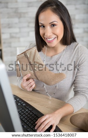 woman holding trendy suede boots and using computer