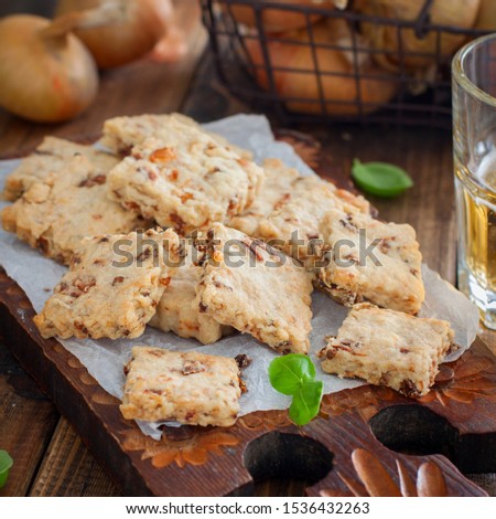 Cracker cookies with fried onions on a wooden board with a glass of beer,square