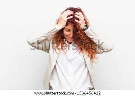 Young natural redhead business woman isolated against white background laughs joyfully keeping hands on head. Happiness concept.