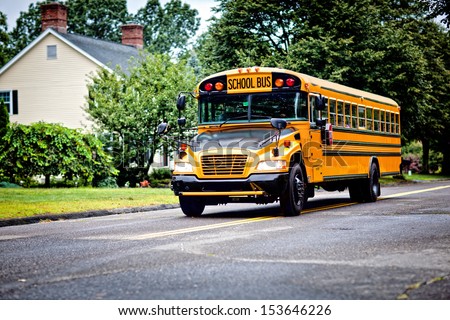 Yellow school bus driving along street Royalty-Free Stock Photo #153646226