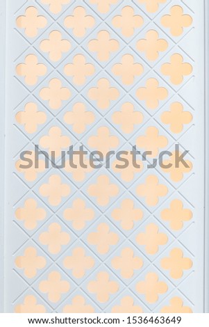 close up view of wooden white partition  or backdrop with four leaf clover pattern hole and yellow light background texture.
