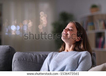 Relaxed homeowner breathing deeply fresh air sitting on a couch in the living room in the night at home Royalty-Free Stock Photo #1536473561