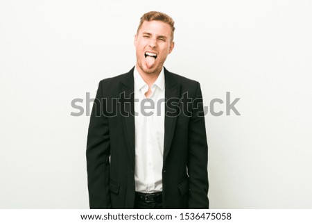 Young caucasian business man funny and friendly sticking out tongue.