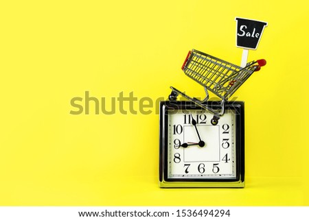 Christmas Black Friday Sale concept with silver clock, shopping cart shop trolley with sign sale on yellow background. Limited edition, Marketing, time planning, outfit layout. Copy space.