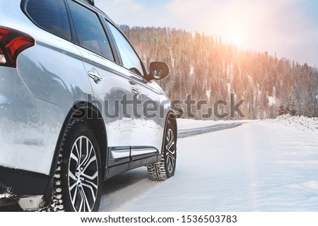 Modern Suv four wheel drive car stay on roadside of winter road. Family trip to ski resort concept. Winter or spring holidays adventure. car on winter snowy road in mountains in sunny day. Royalty-Free Stock Photo #1536503783