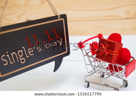 Online shopping of China, 11.11 single's day sale concept. The red shopping cart, red ribbon and red heart pillow on white and brown background with copy space for text 11.11 single's day sale.