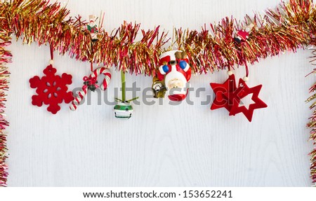 Christmas decorations hanging from red and yellow tinsel. White wood background. Merry Christmas.