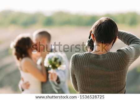 wedding photographer takes pictures of the bride and groom in nature in autumn, the photographer in action