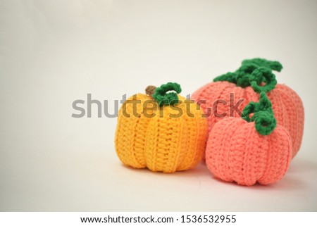 Autumn white background with knitted pumpkins. Side view of knitted pumpkins of different sizes. Happy Thanksgiving Autumn Background. Autumn concept, there is a place for text.
