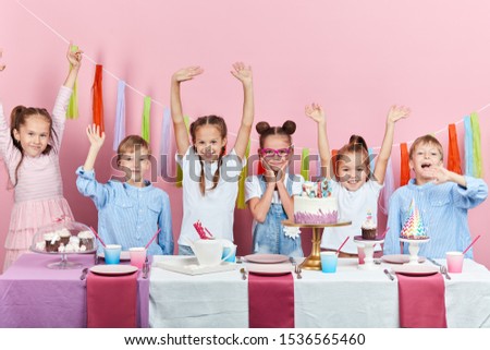 cheerful little boys and girls celebrating birthday, isolated pink background, studio shot.