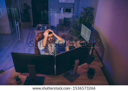 Oh no! Hign angle view photo of it specialist loser guy sitting chair many monitors noticed server debugging holding hands on head need to edit errors night office indoors