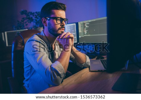 Profile photo of it-specialist guy working late at night sitting office chair looking monitors website debugging expert think how to correct service error office indoors