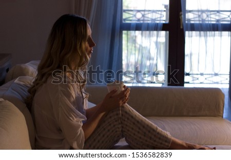 Elegant middle aged woman sitting on the couch and reading news on the tablet. Using tablet pc at home.