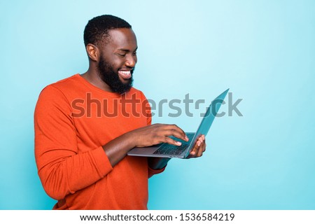 Photo of cheerful man browsing through his laptop smiling toothily making new video which can be watched on his social media isolated vivid blue color background