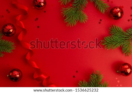 Top view Christmas red background with fir branches, xmas balls, ribbon and sparkles. Merry christmas and Happy New Year card with Space for text